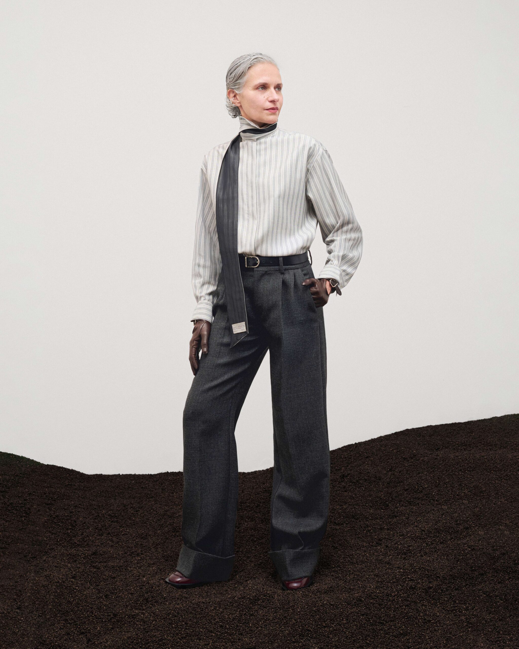 Striped shirt with removable foulard, wide cuffed wool trousers, black leather belt and brown gloves, Durazzi Milano FW26