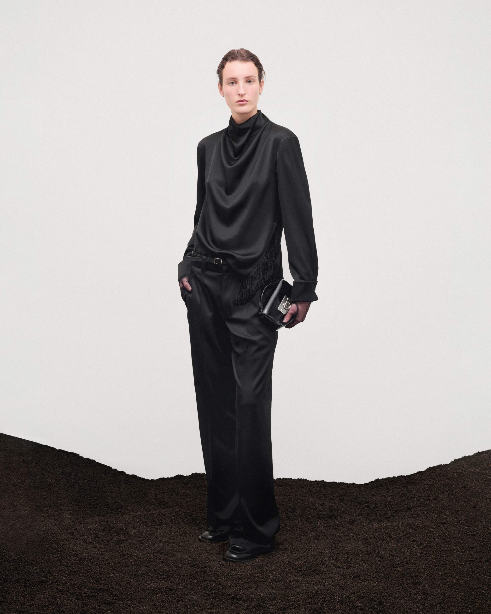 Draped silk cowl-neck top with silken fringing, tailored black trousers and black leather Mini Swing bag, Durazzi Milano FW26